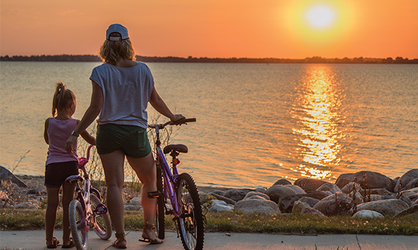 mother and daughter biking on the shore at sunset