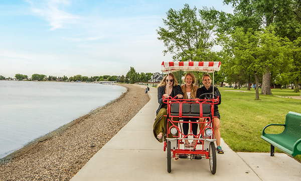 People riding on tandem bike by lake